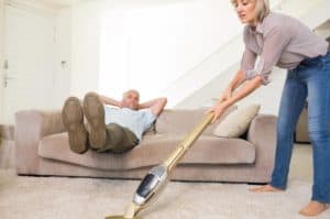 man-resting-on-couch-while-woman-vacuuming-area-rug.jpg